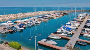 A marina with numerous boats docked, a rocky breakwater, and clear blue water. - Family friendly summer getaway, short walk to beach, restaurants, etc... (Meaford)