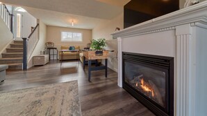 A spacious living room with a fireplace, wooden flooring, a staircase, and a cozy seating area with a sofa and a coffee table. - Family friendly summer getaway, short walk to beach, restaurants, etc... (Meaford)