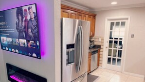 A modern kitchen with stainless steel appliances, a built-in TV, and a water dispenser. - Beautiful Oasis in Fort Lauderdale (Davie)