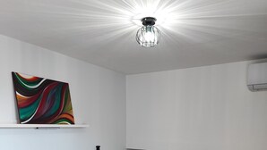 A bedroom with a bed, a colorful abstract painting, a ceiling light, and a white air conditioning unit. - Vacation home in the heart of Petralia Soprana with Breakfast (Petralia Soprana)