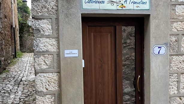 A stone building with a wooden door, a sign above the door, and a number '7' on the wall. - Vacation home in the heart of Petralia Soprana with Breakfast (Petralia Soprana)