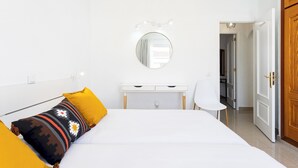 Un dormitorio con cama, mesita de noche, una silla, un espejo y un armario.