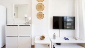 A modern, minimalist room with a white dresser, a flat-screen TV mounted on the wall, and three woven wall hangings. - Home2Book Cozy Coastal Apt & Pool, Los Cristianos (Costa del Silencio)