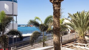 A coastal hotel with a pool area, palm trees, and a view of the sea. - Home2Book Cozy Coastal Apt & Pool, Los Cristianos (Costa del Silencio)