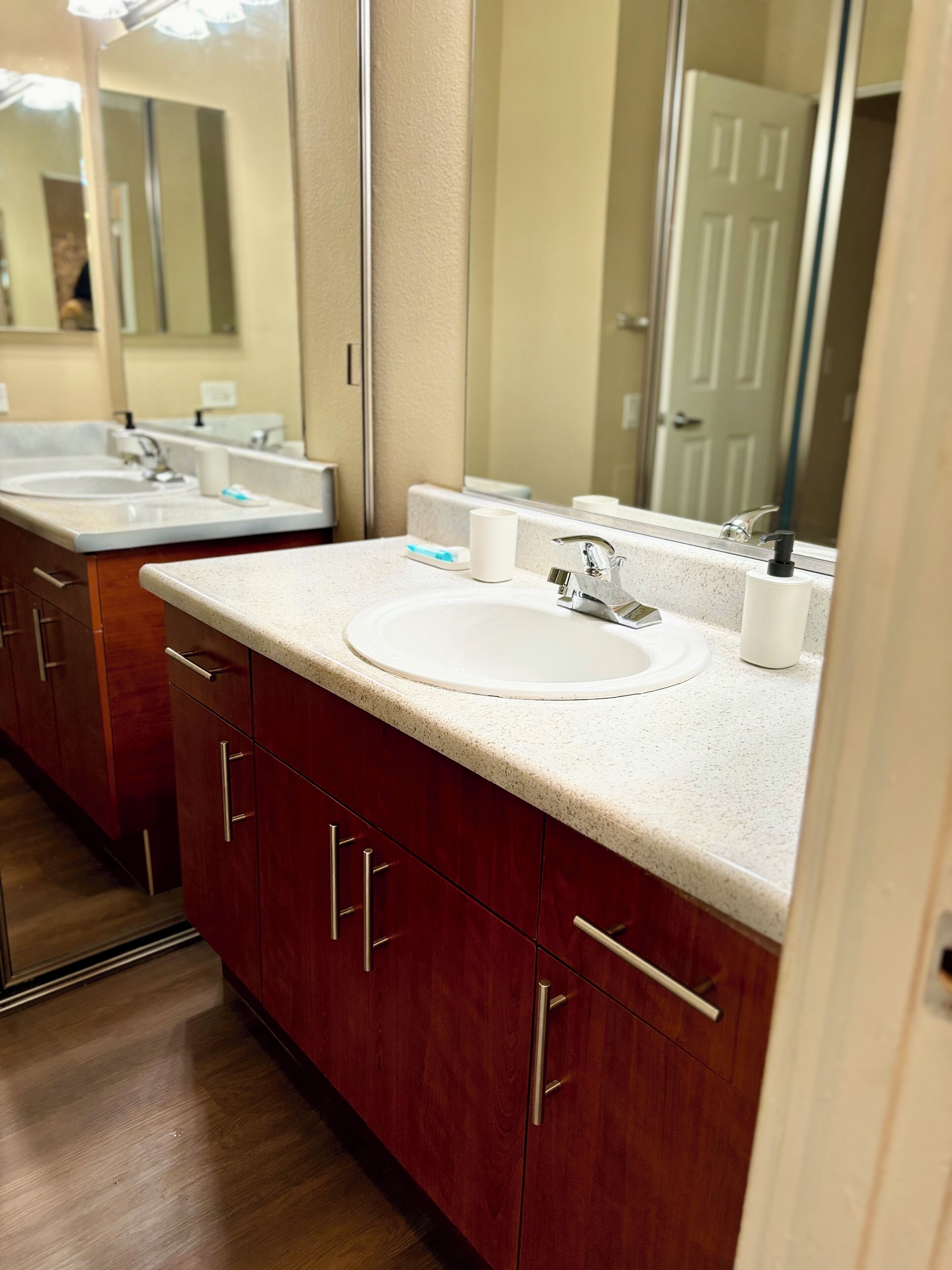 A bathroom with a white sink, a mirror, and a door in the background.
