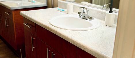 A bathroom with a white sink, a mirror, and a door in the background.