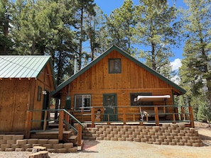 A wooden cabin with a porch, steps, and a chimney.