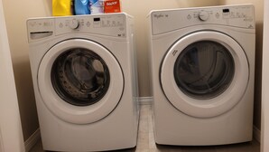 Twee voorladers wasmachines in een wasserij, met wasmiddelflessen erboven.