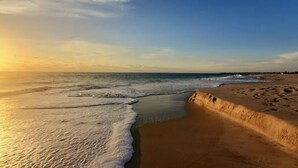 A beach with waves, a sandy area, and a structure on the right.