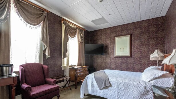 Une chambre d’hôtel comprenant un lit, un bureau, une chaise, une télévision et une lampe.