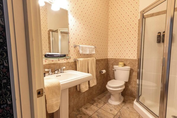 A bathroom with a sink, mirror, toilet, and shower. - Lily of the Valley Room - Big Tree Inn
(Geneseo)