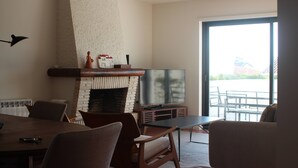 A living room with a fireplace, a television, and a dining area with chairs and a table.