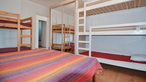 A dormitory room with bunk beds, a striped bedspread, and a sliding door leading to another room. - Pet friendly home in Cornillon (Cornillon)