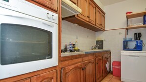 A kitchen with wooden cabinets, a white oven, a microwave, and a sink. - Pet friendly home in Cornillon (Cornillon)