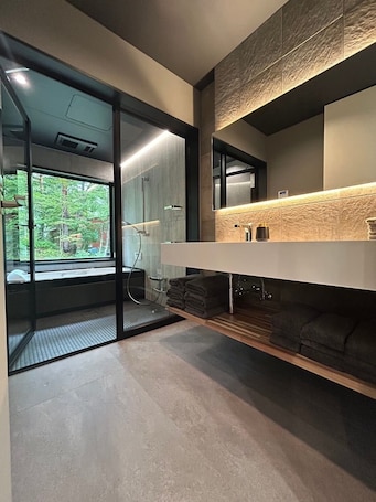 Un baño moderno con un espejo grande, cabina de ducha de vidrio y vistas a zonas verdes.