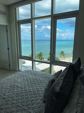 Quarto com uma grande janela com vista para a praia e oceano.