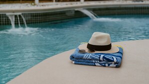 A poolside area with a hat, sunglasses, and a towel on a table. - Private Heated Pool Villa / 15 mins to Disney /Firepit /Game Room (Kissimmee)