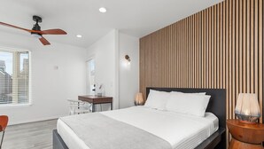 A modern bedroom with a large bed, a desk, and a chair.