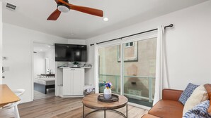 A modern living room with a wooden floor, a round coffee table, a sofa, and a television mounted on the wall.