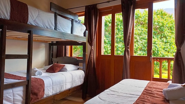 Una habitación con literas, un ventanal con cortinas y vista a zonas verdes.