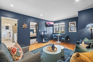 Un salon moderne avec un mur bleu foncé, une table basse ronde, un canapé et un téléviseur fixé au mur.
