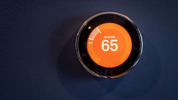 Termostato con pantalla digital que muestra una temperatura de 18 grados Celsius.