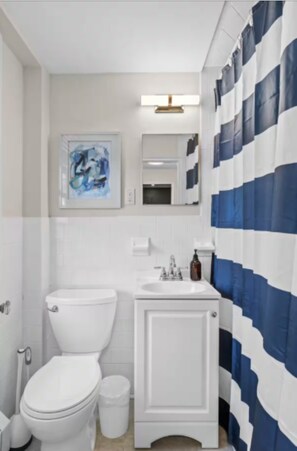 Une salle de bain équipée de toilettes, d’un lavabo et d’un rideau de douche bleu et blanc à rayures.