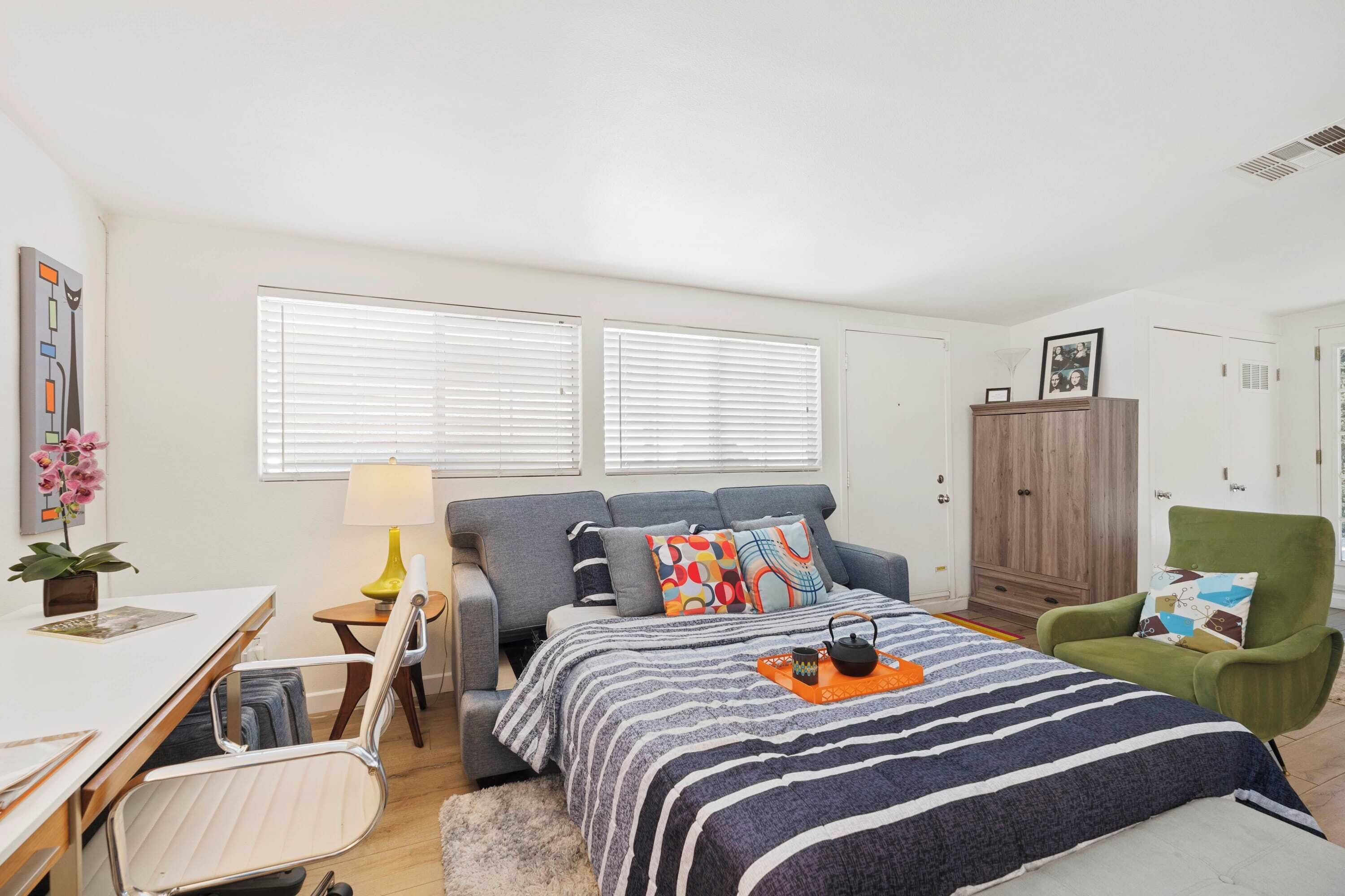 A bedroom with a bed, a desk, a chair, a lamp, and a wardrobe.