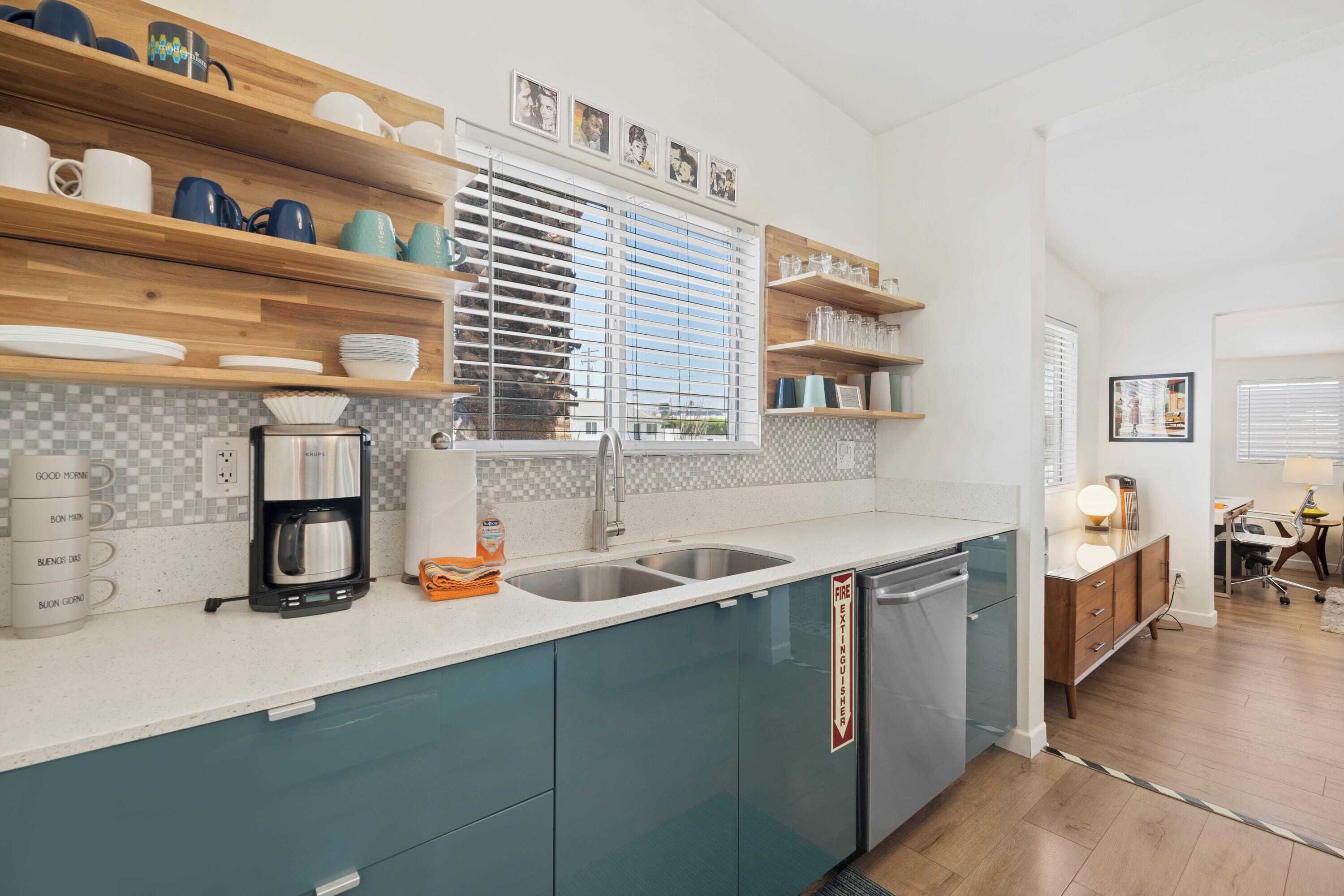 A modern kitchen with teal cabinets, a coffee maker, and a dishwasher.