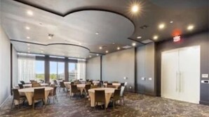 A conference room with round tables and chairs, a patterned carpet, and a large window with a view.