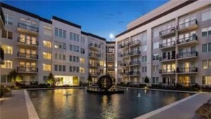 A modern hotel with a central courtyard pool, multiple balconies, and a well-lit facade.