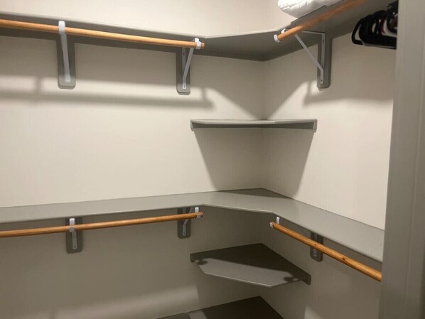 Un placard d’angle avec des étagères grises et des supports en bois.