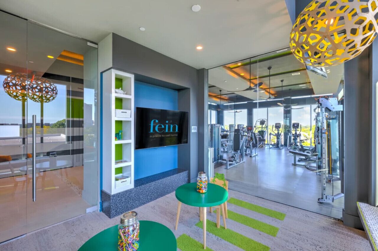 A modern fitness center with a large screen displaying the word "fein" and various exercise equipment.