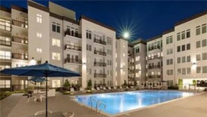A swimming pool surrounded by a building with multiple floors and balconies. - Fully Furnished 2b/2b Apartment in the Galleria (Houston)