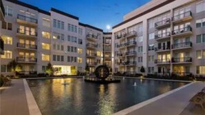 A modern hotel with multiple floors, a central courtyard with a pool, and a decorative fountain. - Fully Furnished 2b/2b Apartment in the Galleria (Houston)