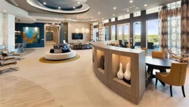 A spacious hotel lobby with a central reception desk, seating areas, and large windows offering views. - Fully Furnished 2b/2b Apartment in the Galleria (Houston)