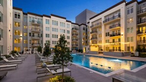 A modern hotel with a swimming pool, lounge chairs, and a well-lit outdoor area. - Spacious 3B 2.5B Apt by Galleria (Houston)
