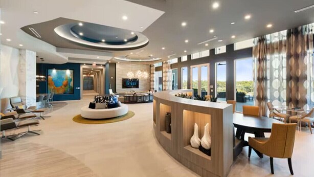 A spacious hotel lobby with a central seating area, a reception desk, and large windows offering a view. - Spacious 3B 2.5B Apt by Galleria (Houston)
