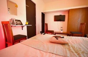 A hotel room with a bed, a desk, a chair, a television, and a wardrobe. - Continental Lebe inn (vada nemmeli)