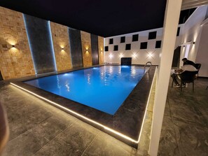 A rectangular indoor swimming pool with a dark blue water surface, surrounded by a dark floor and walls. - Continental Lebe inn (vada nemmeli)