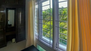 Ein Zimmer mit einem großen Fenster, einem Kleiderschrank und einem Spiegel.