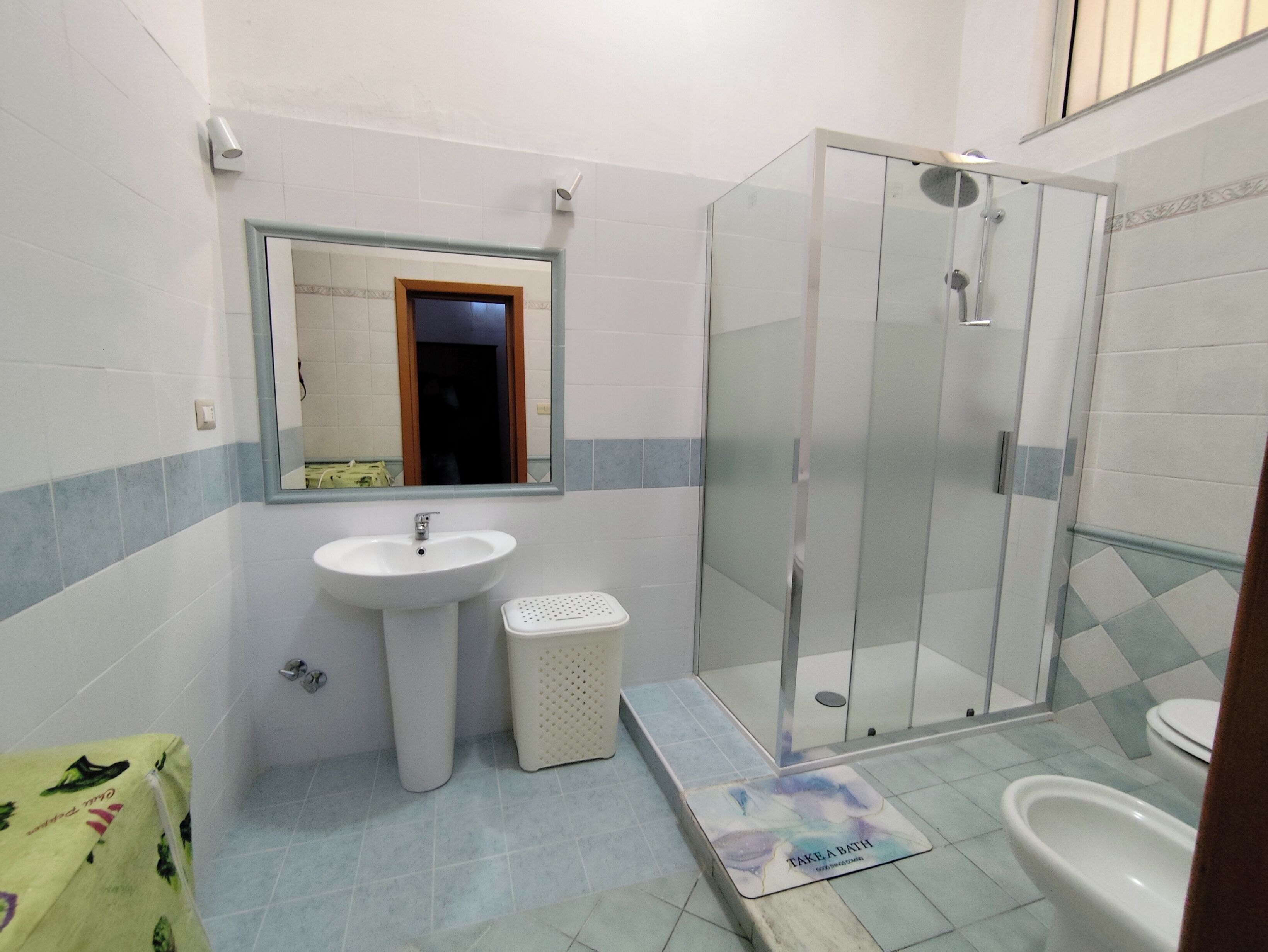 Een badkamer met een wastafel, spiegel, douche en toilet.