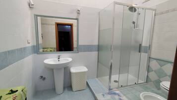 Een badkamer met een wastafel, spiegel, douche en toilet.