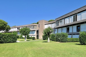Un bâtiment moderne doté d’un toit plat, de grandes fenêtres et d’une cour intérieure agrémentée d’arbres et d’une pelouse.