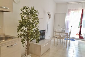 Una cucina moderna con lavandino, un'area pranzo con tavolo e sedie, e una pianta in vaso.