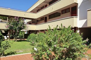Un edificio de varios pisos con balcones y un pequeño jardín.