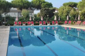 Una piscina con sedie a sdraio rosse e ombrelloni a scacchi.