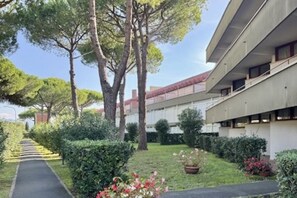 Un edificio moderno con un camino central bordeado por árboles y arbustos.