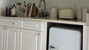 A kitchen with white cabinets, a sink, a toaster, and a small refrigerator.