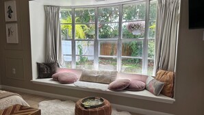 A cozy room with a large bay window, a cushioned bench, and a round ottoman.